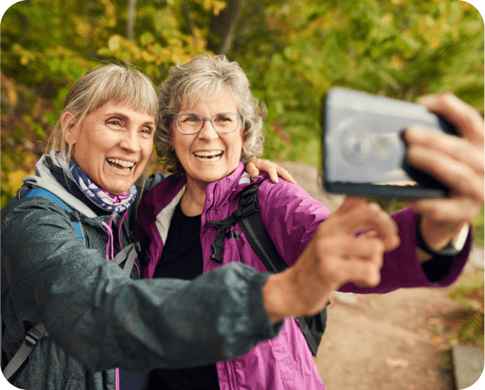 Two older women smiling and posing together for a selfie, capturing a joyful moment of friendship